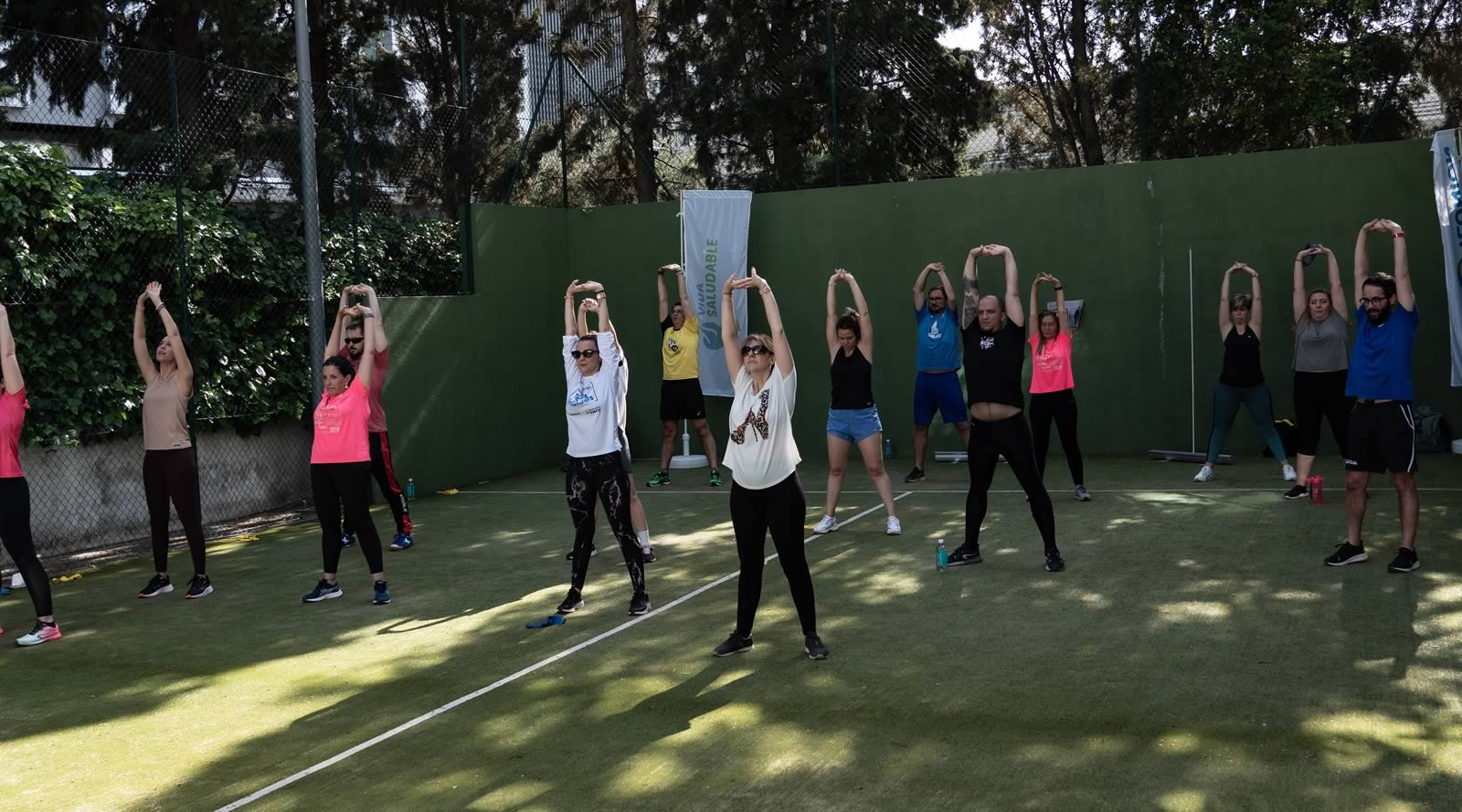 ILUNION Semana de la Salud 2023. Trabajadores de ILUNION realizando estiramiento en pista al aire libre