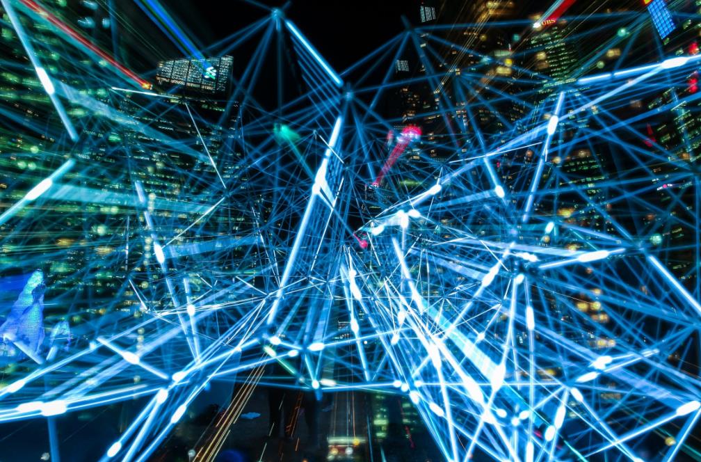 Fotografía nocturna de una gran urbe con multitud de destellos azules que simulan la velocidad de las comunicaciones digitales y tecnológicas