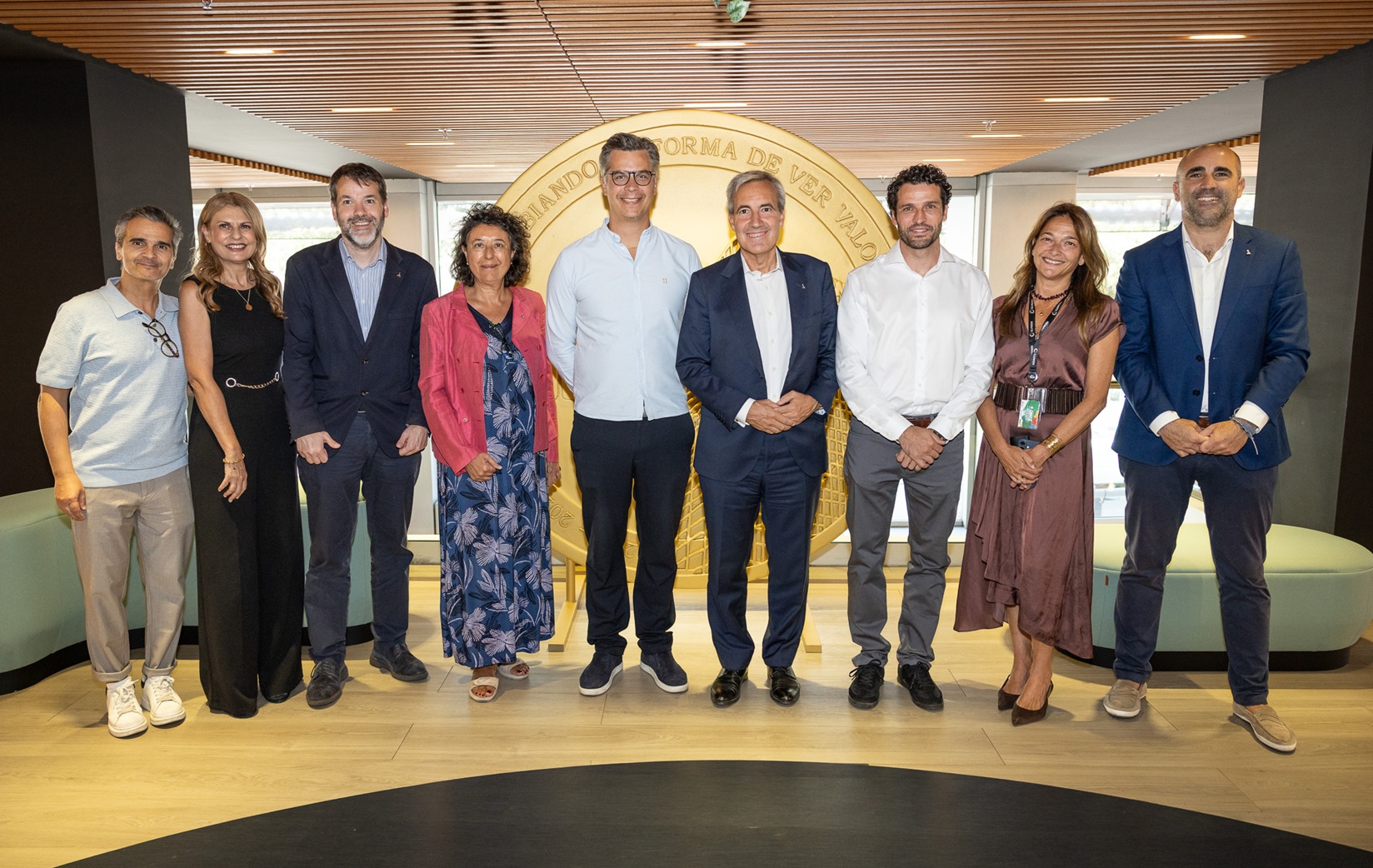 Grupo de ocho personas posando en un espacio corporativo, frente a un gran elemento circular decorativo, durante un encuentro institucional entre IKEA e ILUNION.