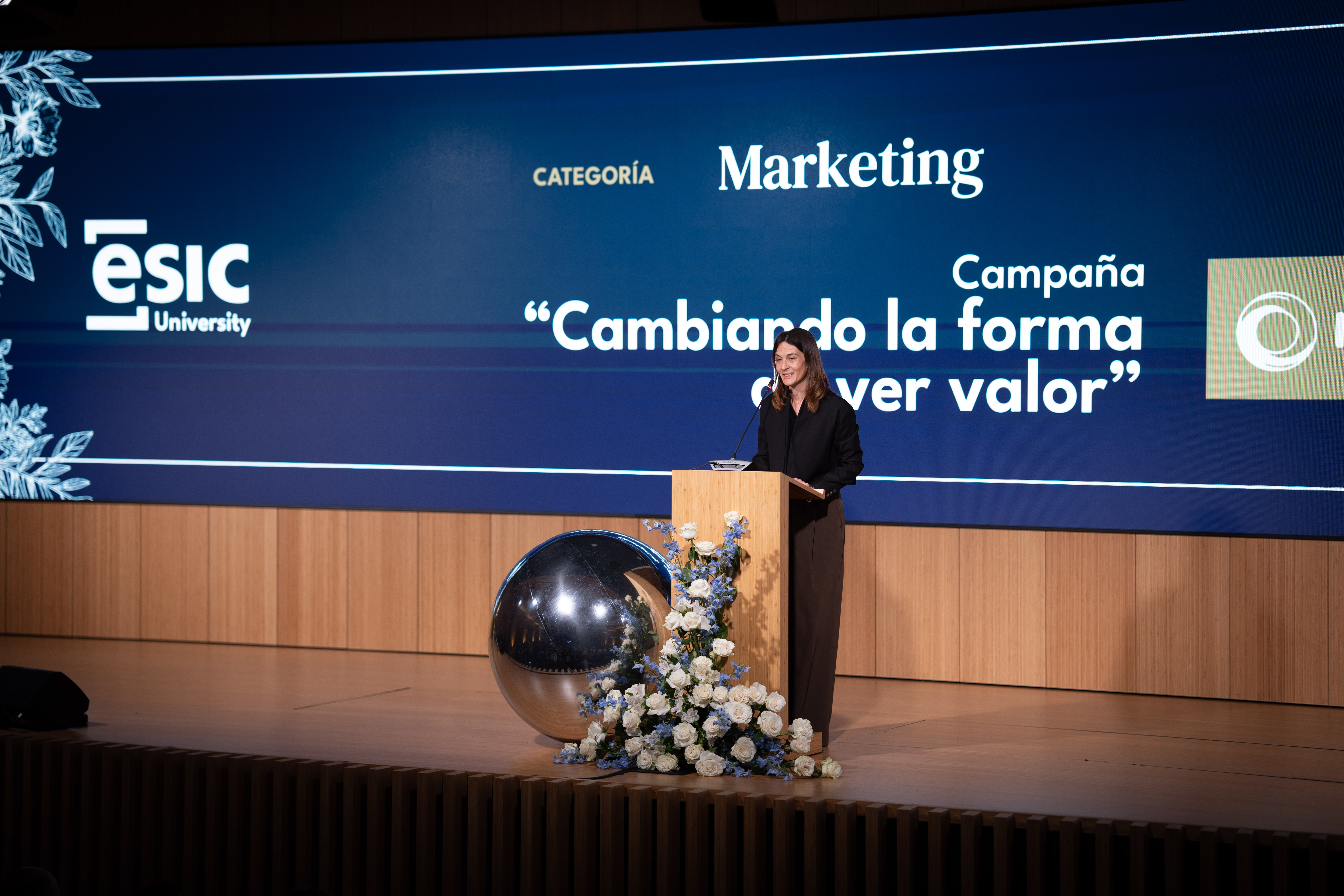 Escenario con pantalla de ESIC University: categoría Marketing y campaña “Cambiando la forma de ver valor”, persona hablando desde un atril.