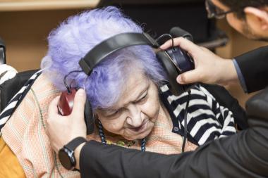 Fotografía de una mujer mayor a quien le están colocando unos auriculares para una audiometría