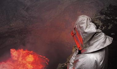 Una persona con un traje aluminizado observa de cerca un río de lava 