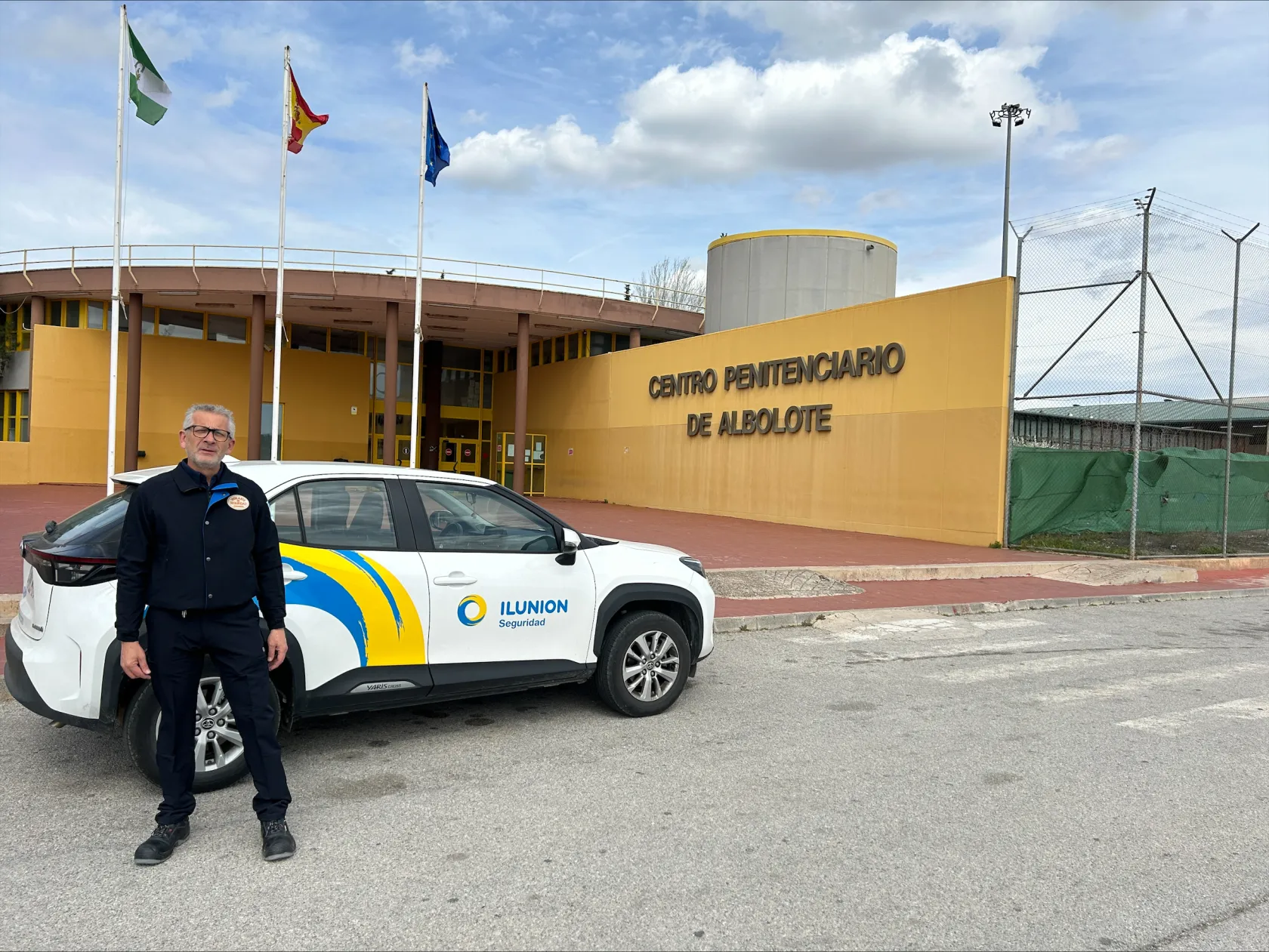 Un vigilante de seguridad de ILUNION con su vehículo, frente al centro penitenciario de Albolote 
