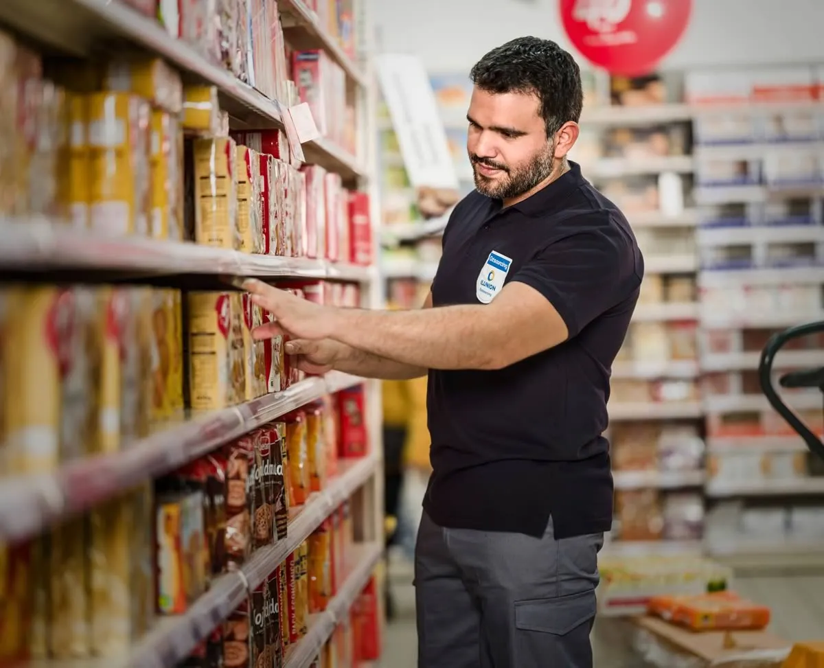 Un trabajador de ILUNION repone el lineal de un supermercado