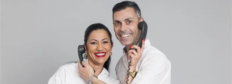 Dos personas con un teléfono en el oído y sonriendo