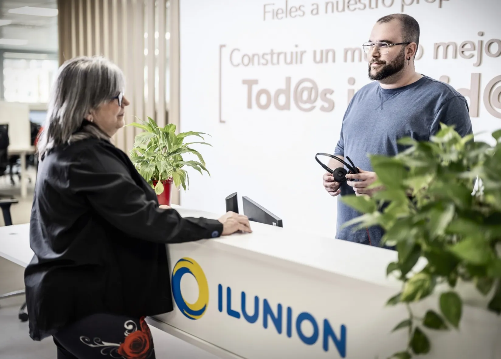 Un trabajador de ILUNION Contact Center BPO atiende a una mujer senior en recepción