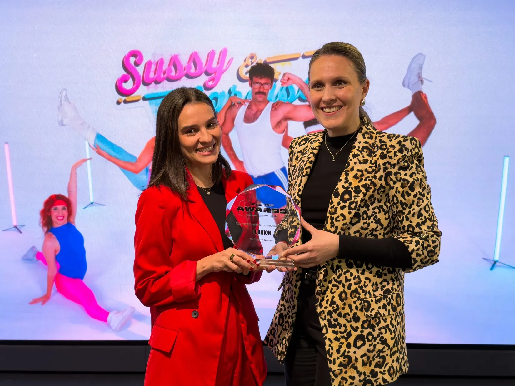 Andrea Durán sostiene el premio otorgado a ILUNION junto a una compañera de ILUNION Comunicación Social