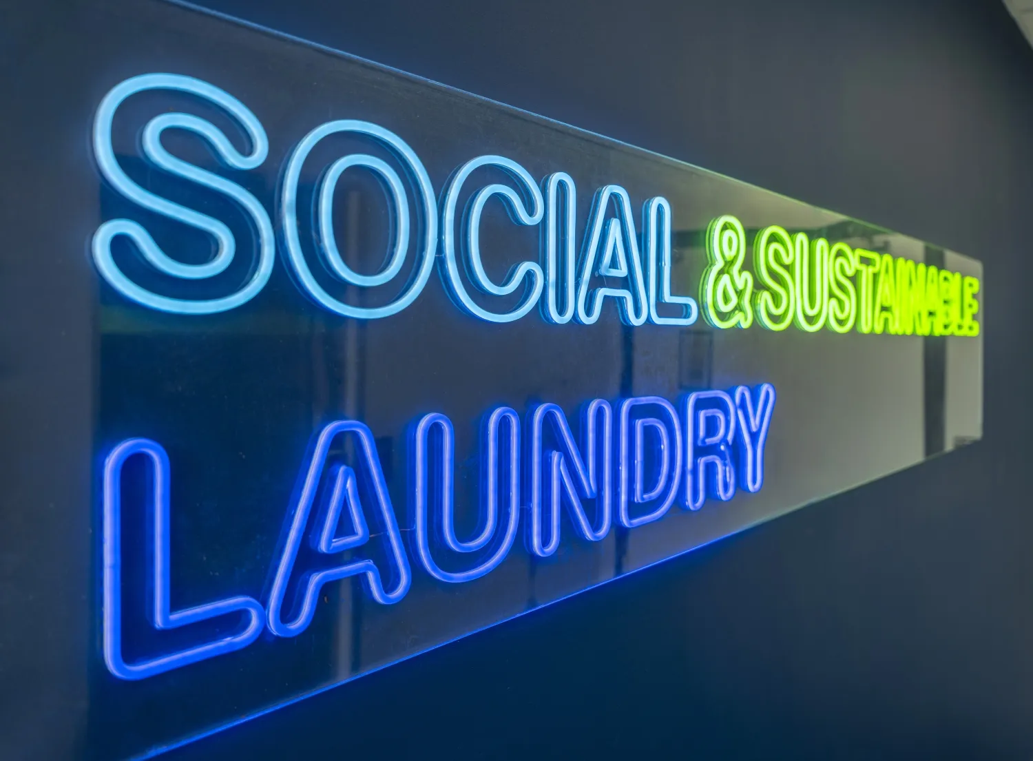 Un letrero de neon en el que se lee Social and sustainable laundry