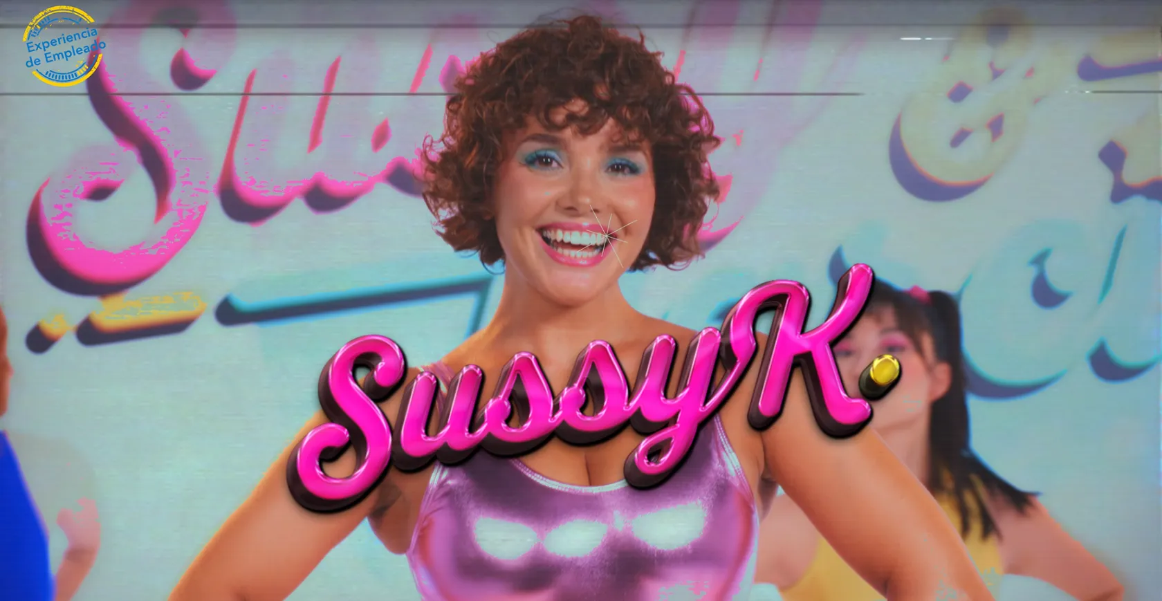 Persona en primer plano con top rosa metalizado y maquillaje llamativo, sonriendo con fondo colorido; texto destacado “SusoyK