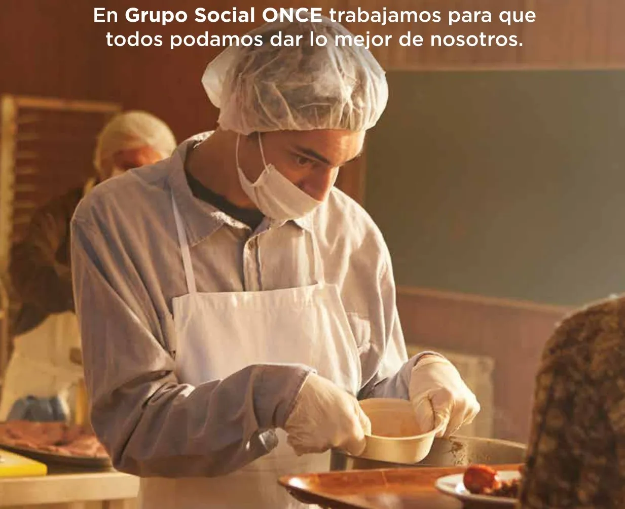 Imagen de uno de los carteles de la campaña donde se ve a un cocinero poner comida en la bandeja de otra persona, junto al texto "En Grupo Social ONCE trabajamos para que todos podamos dar lo mejor de si mismos"