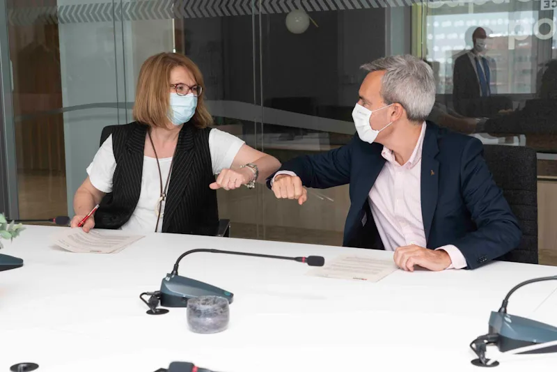 De izquierda a derecha, la presidenta de Amica, Mercedes del Hoyo, y el consejero delegado de ILUNION, Alejandro Oñoro, se saludan con el codo