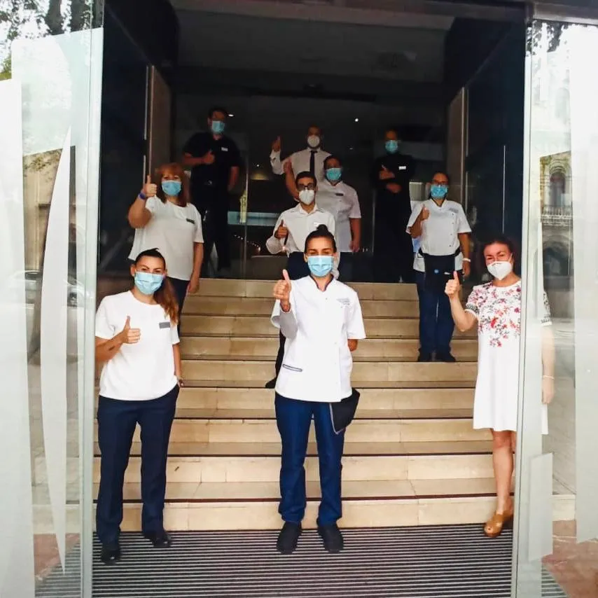 Imagen de los trabajadores del ILUNION Bel Art en la entrada del hotel con EPI, mascarillas y respetando las distancias de seguridad 