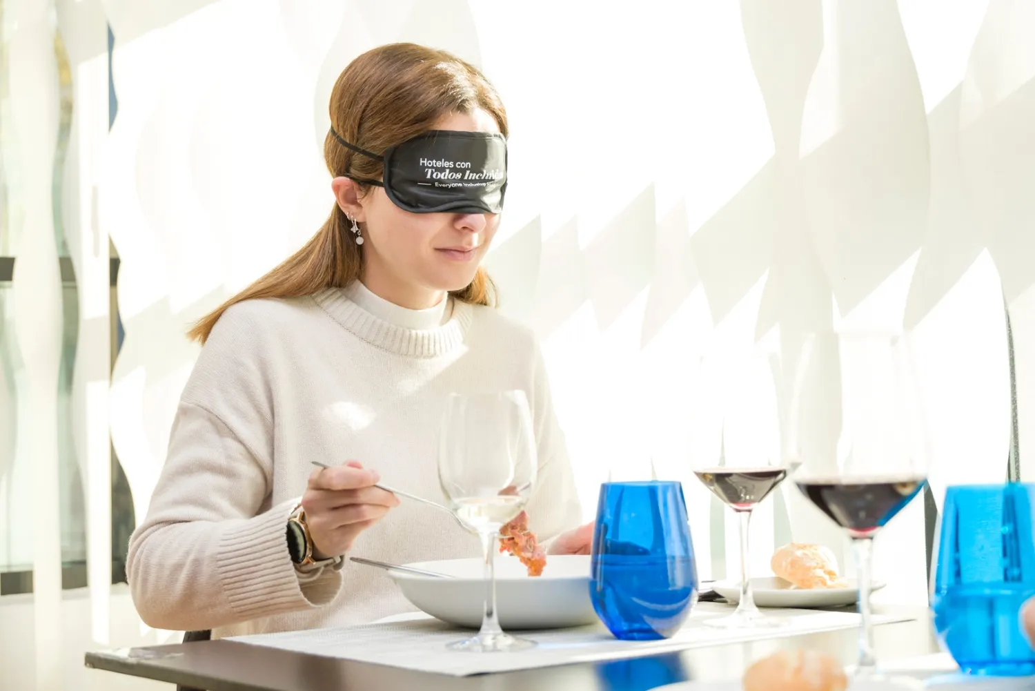 Imagen de una mujer con los ojos tapados con un tenedor llevándose comida a la boca