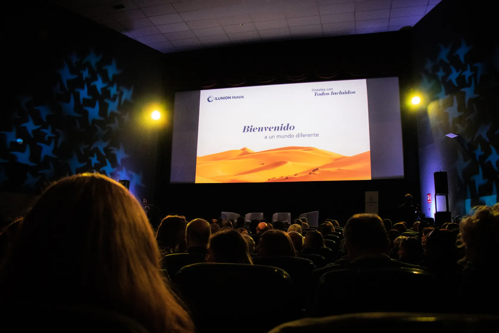 Fotografía durante el estreno. En la pantalla se lee 'ILUNION Hotels. Hoteles con todos incluidos. Bienvenidos a un mundo diferente'.