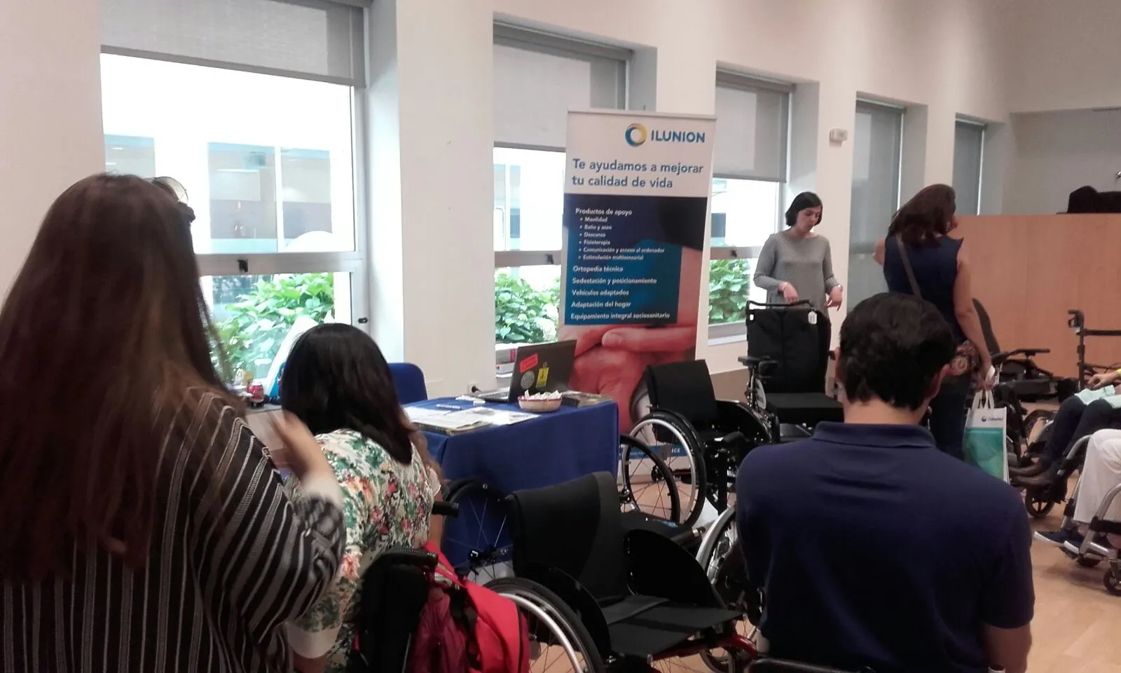 Asistentes a las jornadas de Aspaym observando los productos de ILUNION Salud 