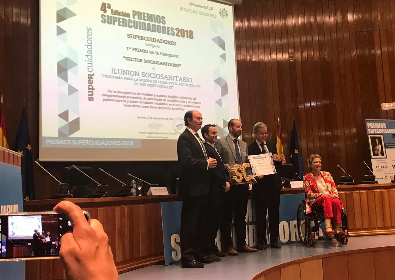 En la imagen, el director general de ILUNION Sociosanitario, Joaquín Leizaola, sujetando el diploma; Pedro Pérez, responsable del Servicio de Prevención Mancomunado de ILUNION Sociosanitario, sosteniendo el galardón; junto con la secretaria de Estado de Servicios Sociales, María Pilar Díaz