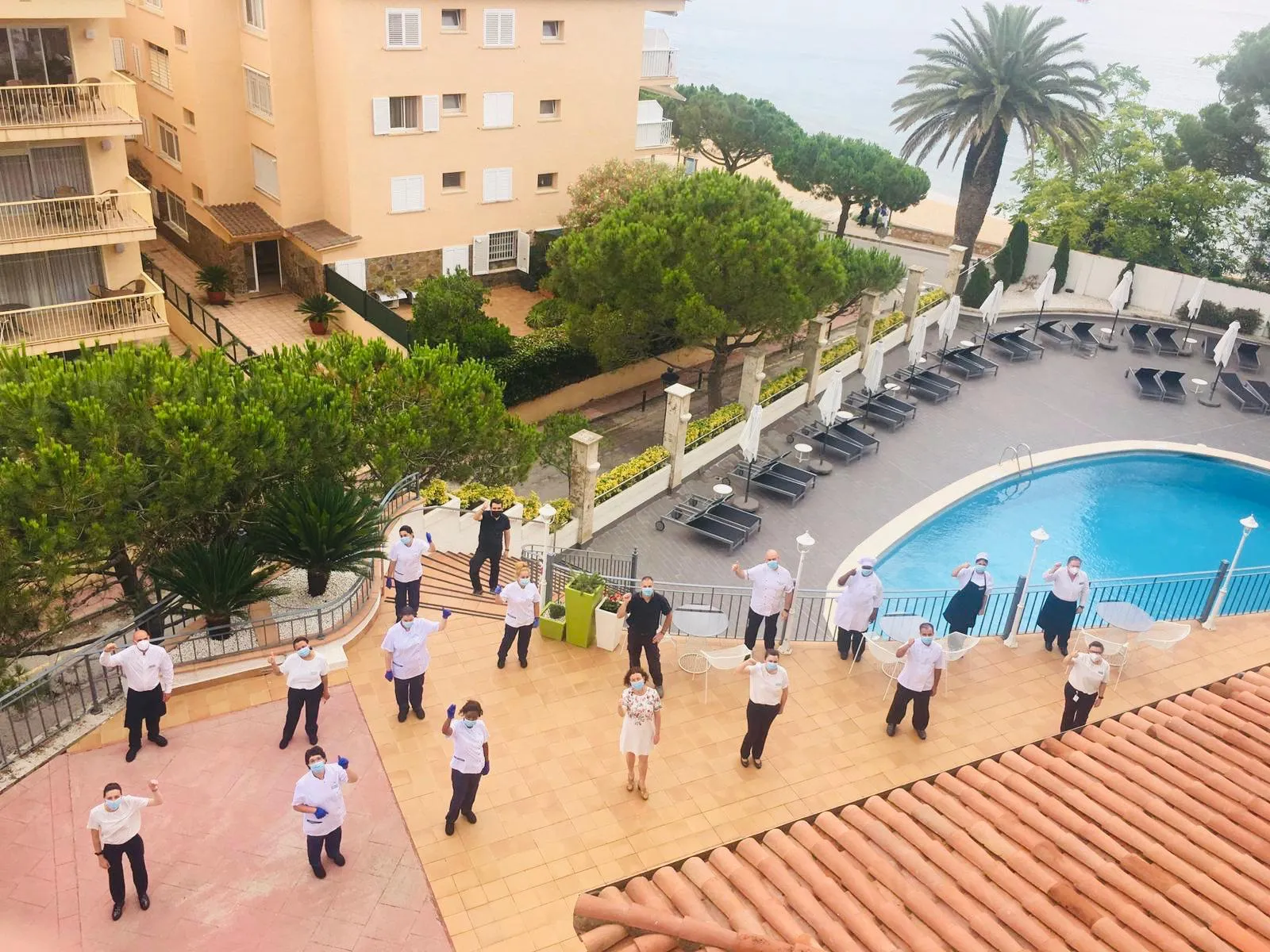 Imagen de los trabajadores del ILUNION Caleta Park en el exterior del hotel, manteniendo las distancias de seguridad y con sus EPI 